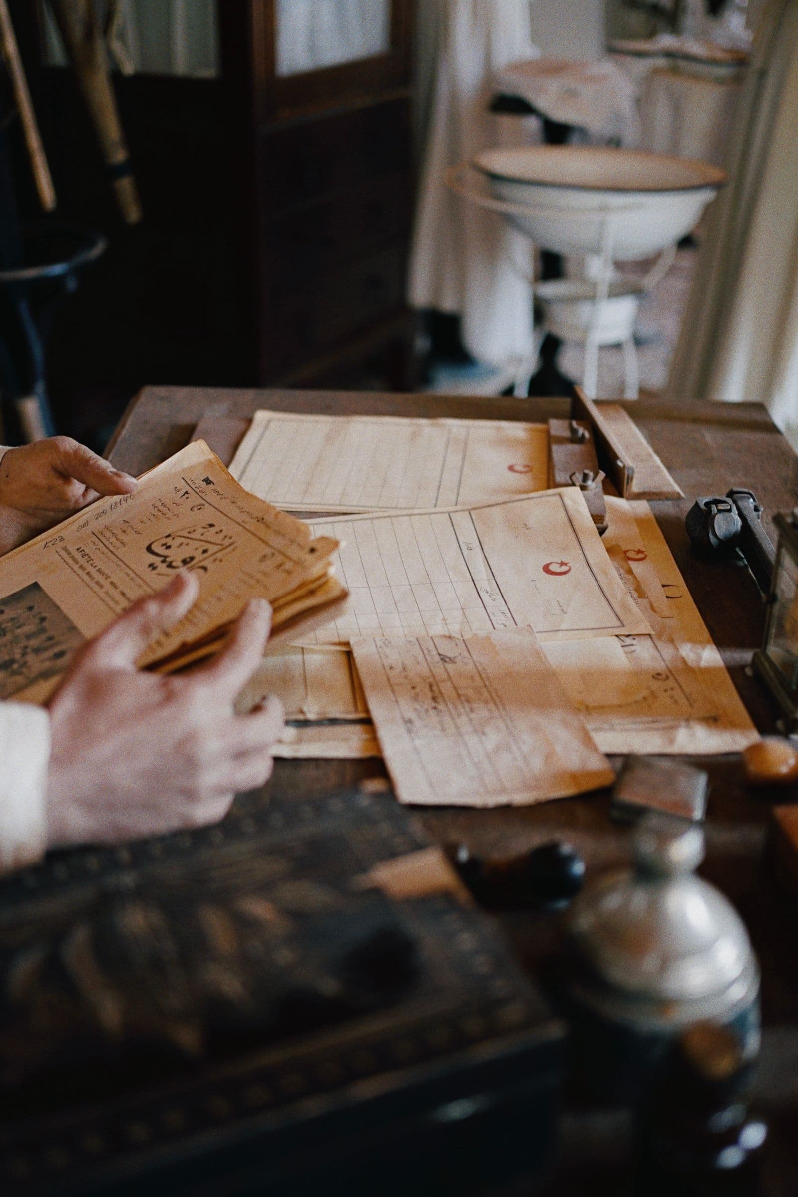 Des documents classés sur un bureau en bois, en lumière basse.
