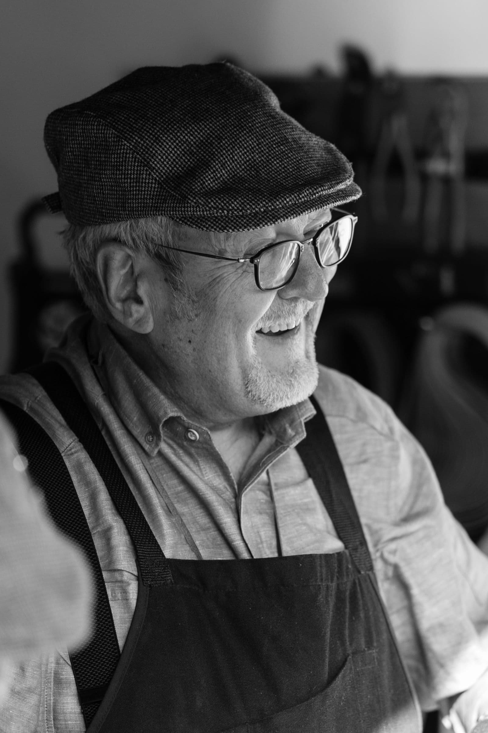 Un artisan senior en tablier et casquette, dans son atelier.