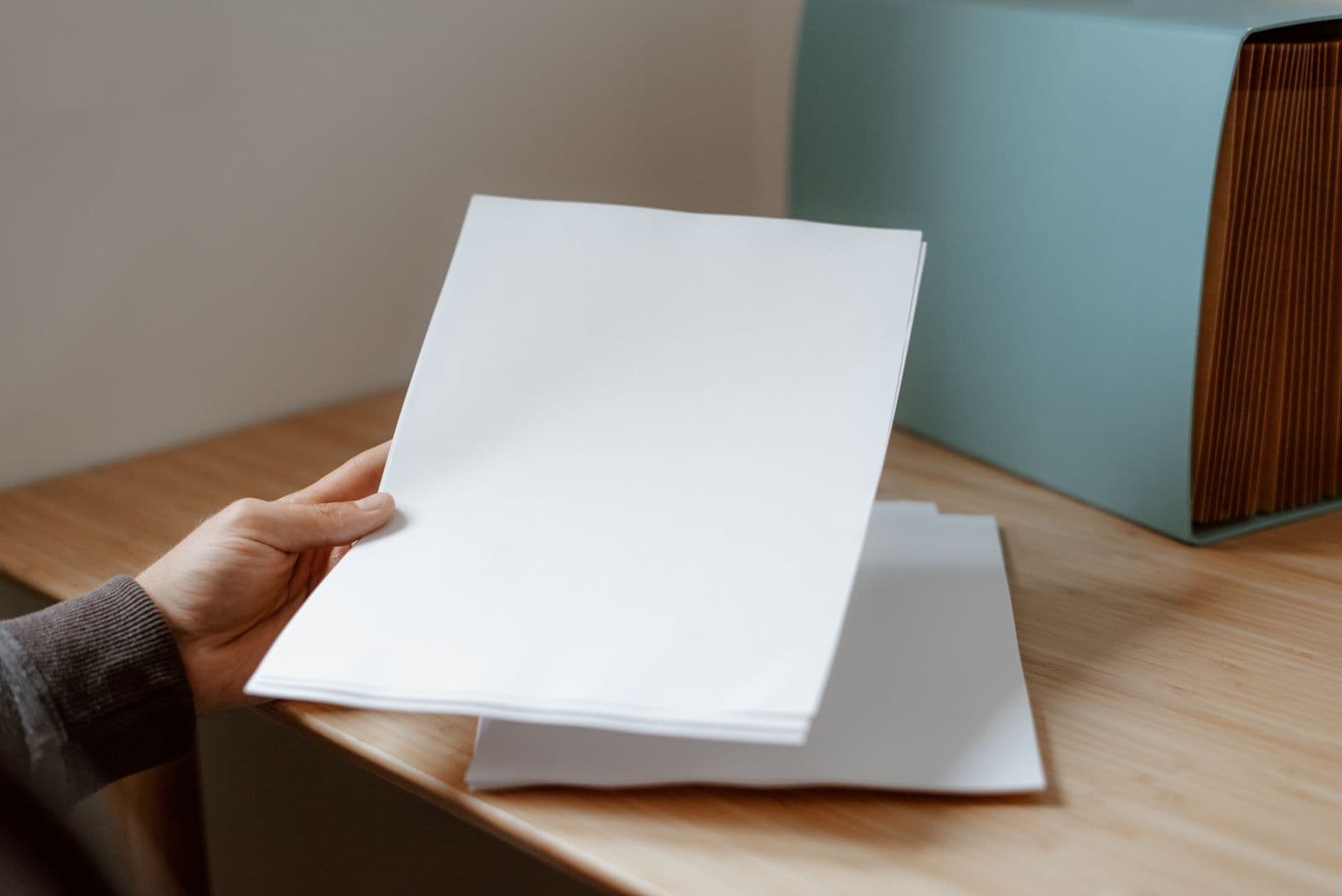 Des mains prennent une feuille posée à côté d'un dossier.